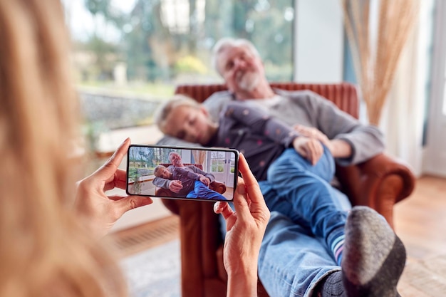 Grandmother taking picture of grandfather and granddaughter\
having daytime sleep at home together