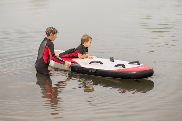 Grandmother trains her grandson surfing in wetsuit