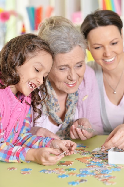 Grandmother with daughter and little granddaughter collecting puzzle