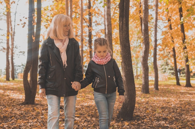 Grandmother with granddaughter in autumn park generation and family concept