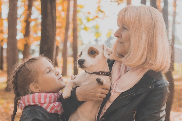 Grandmother with granddaughter in autumn park girl hugging grandmother and her jack russell terrier