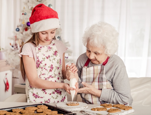 Grandmother with granddaughter decorate cookies