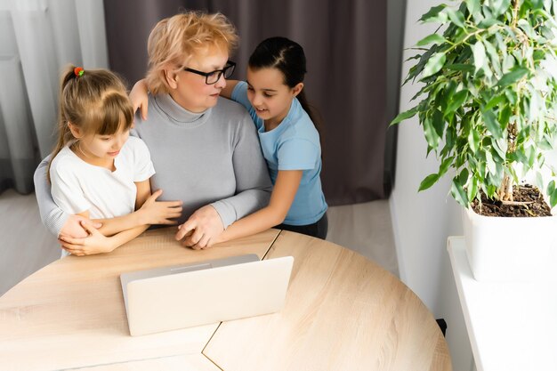 Grandmother with granddaughters use a computer.