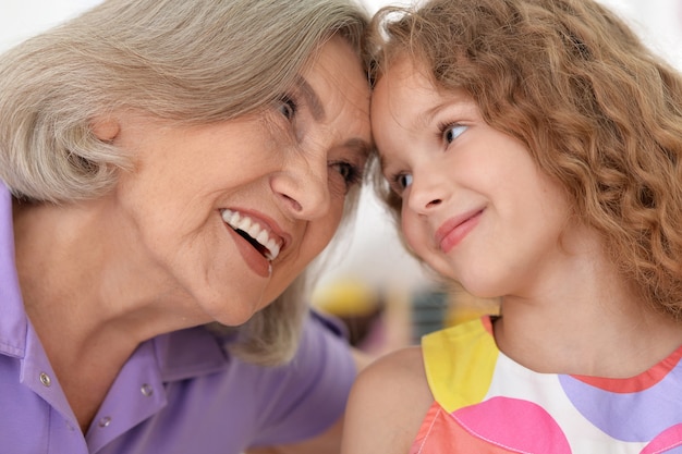 Photo grandmother with her cute  granddaughter on background