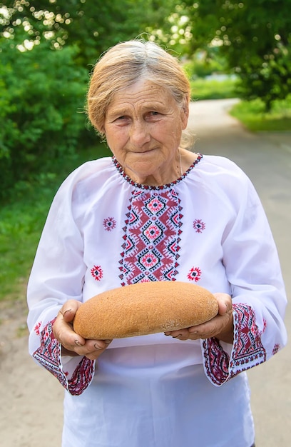 写真 彼女の手にウクライナのパンを持つ祖母選択的な焦点