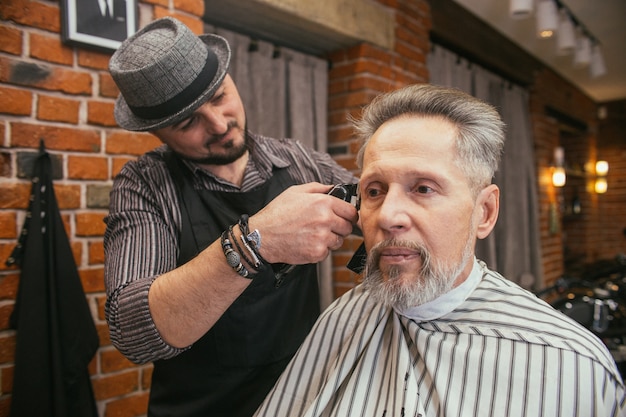 Il nonno si fa tagliare i capelli dal parrucchiere nel negozio di barbiere