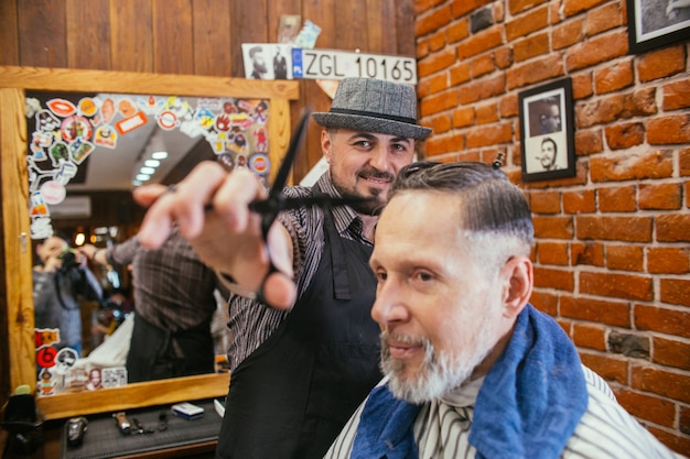 Foto il nonno si fa tagliare i capelli dal parrucchiere nel negozio di barbiere.