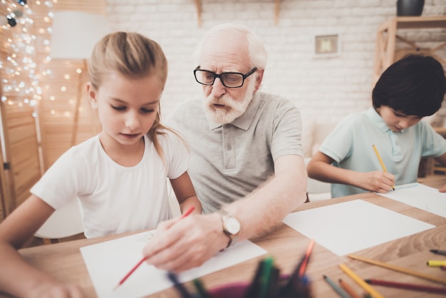 Il nonno insegna ai bambini a disegnare insieme il tempo felice.