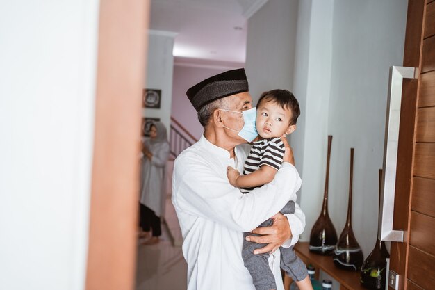 Grandparent kissing his granchild at home during visit celebrating eid mubarak with family together