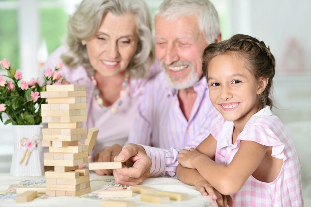 Grandparents and granddaughter playing with wooden blocks