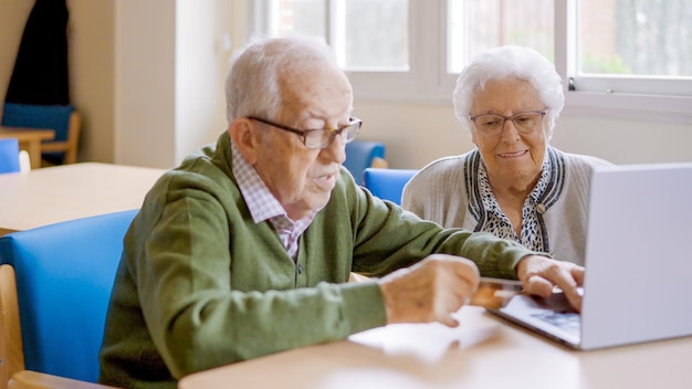 Photo grandparents shopping online using credit card and laptop