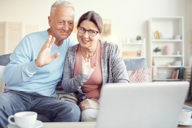 Grandparents waving hands to laptop webcam