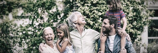 Grandparents with grandchildren and son standing in yard