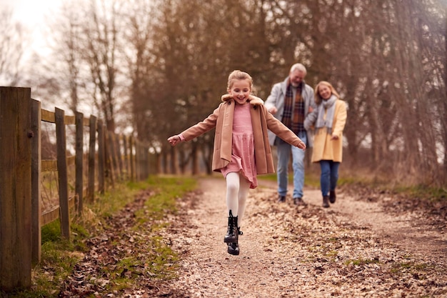 Бабушка и дедушка с внучкой на прогулке по зимней сельской местности