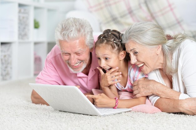 Grandparents with her granddaughter using laptop at home