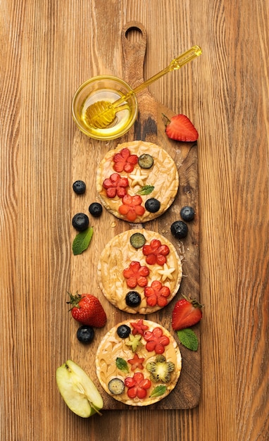 Granen sandwiches met pindakaas met fruit en bessen met honing op een houten bord, bovenaanzicht. Gezond lekker ontbijt
