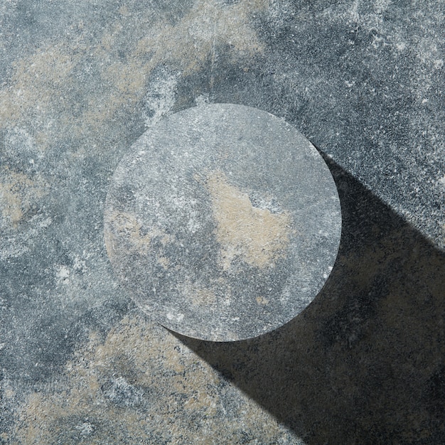 어두운 돌 배경에 그림자가 분리된 화강암 원, 평평한 위치