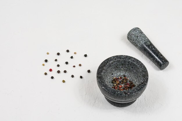 Granite gray mortar with pestle on a white background with pepper Stone mortar is an important tool in cooking pepper food