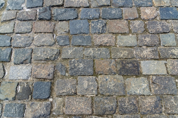 Гранитный камень текстуры тротуара. Конспект старого крупного плана мостоваой булыжника каменного.