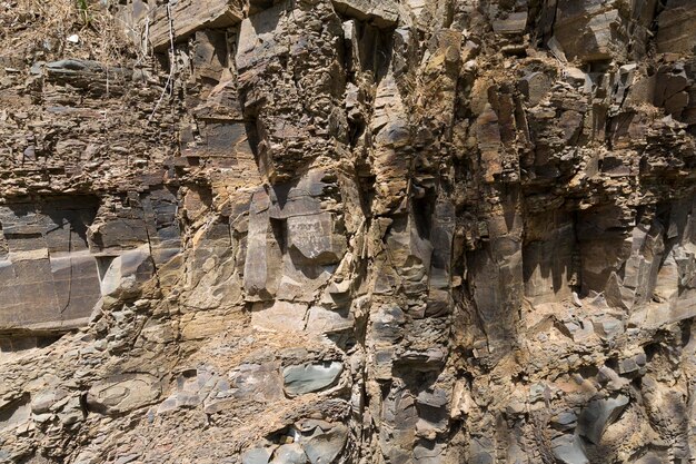 花崗岩の壁。時間によって破壊された岩の一部のクローズアップ。ダークグレーの石。高品質の写真