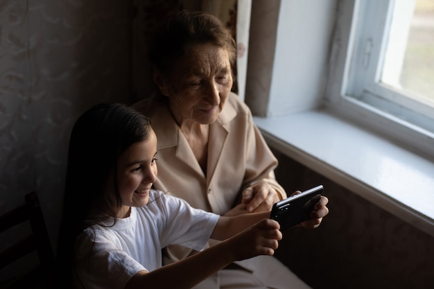 おばあちゃんと孫娘。かわいい女の子が祖母にスマートフォンを見せます。