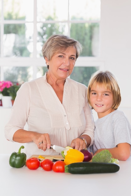 Granny cutting vegetables with her grandson 