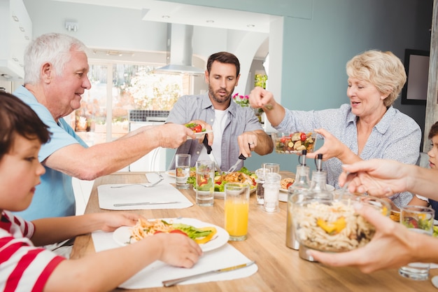 Granny giving food to granddad while sitting at dining table