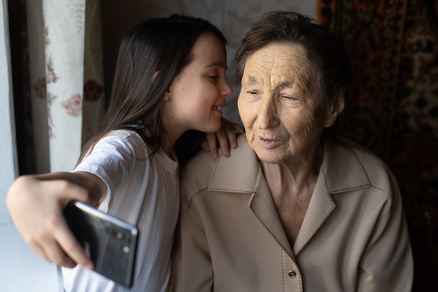 Granny and granddaughter. A cute little girl shows her grandmother a smartphone.