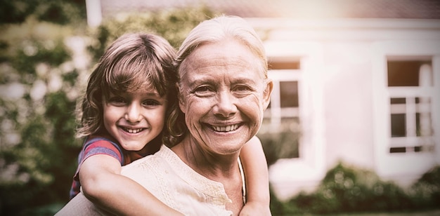 Granny piggybacking grandson in yard