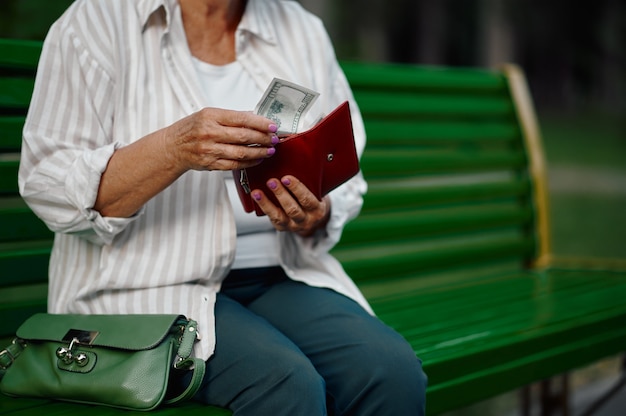 Granny takes money out of her wallet in park