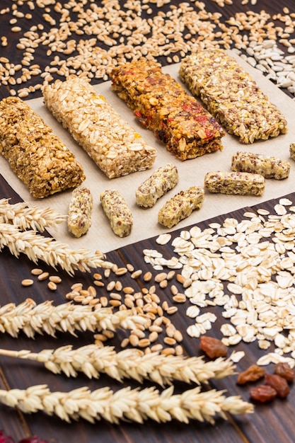 Foto barretta ai cereali. spighette di grano, chicchi di grano, farina d'avena. cibo vegetariano dieta sana. vista dall'alto. superficie in legno scuro. avvicinamento