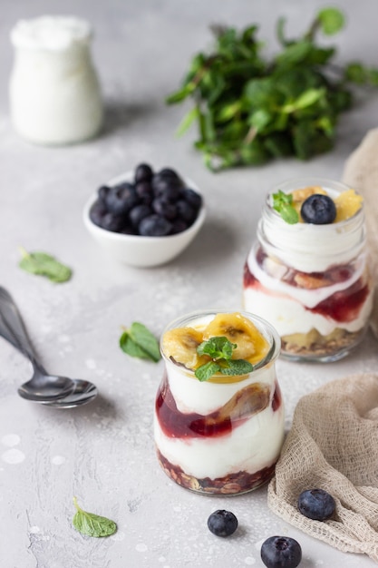 Granola, blueberry and banana greek yogurt parfaits in mason jars 