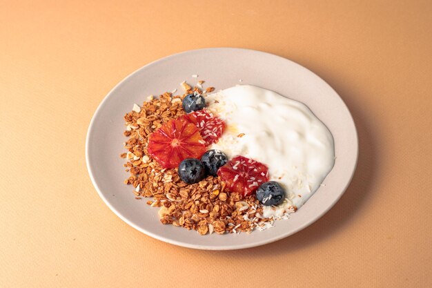 Ciotola di muesli decorata con arance rosse mirtillo e fondo beige di cocco