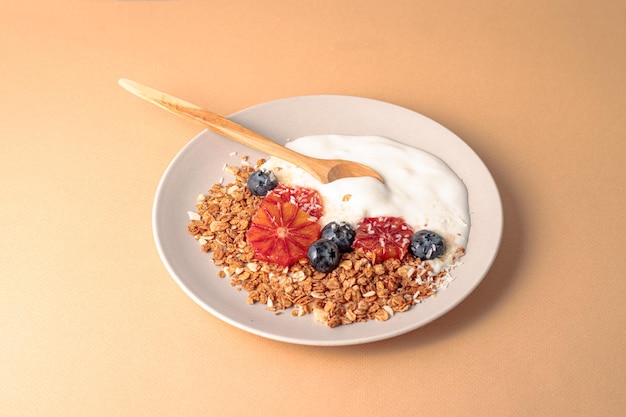 Ciotola di muesli decorata con arance rosse mirtillo e fondo beige di cocco