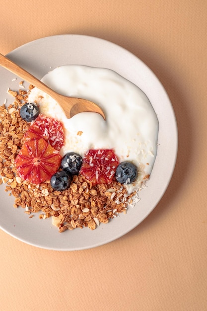 Granola bowl decorated with blood oranges blueberry and coconut beige background