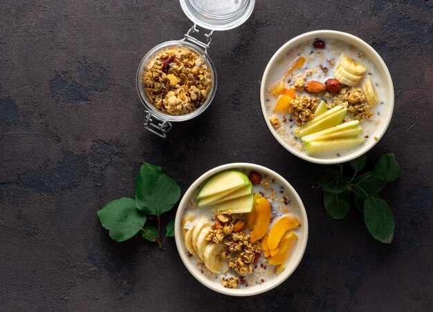 Granola breakfast with fruits, nuts, milk and peanut butter in bowl. Healthy breakfast cereal top view 