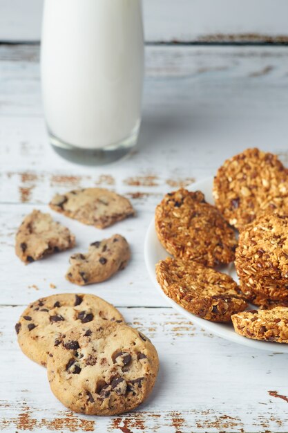 Granola cookies and glass cup of milk on wooden surface.