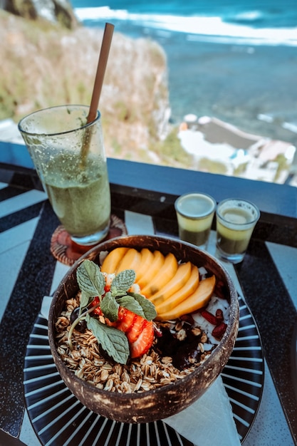 海の景色と健康的な朝食のグラノーラフルーツヨーグルト
