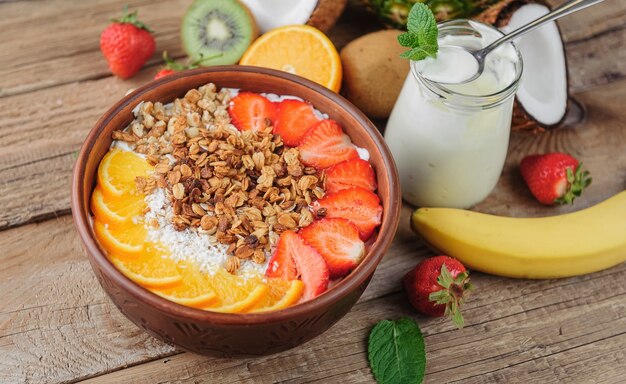 Granola met Griekse yoghurt en fruit op een houten ondergrond in rustieke stijl