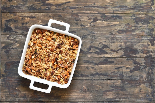 Granola met honing en noten in een ovenschaal op een houten ondergrond Uitzicht van bovenaf