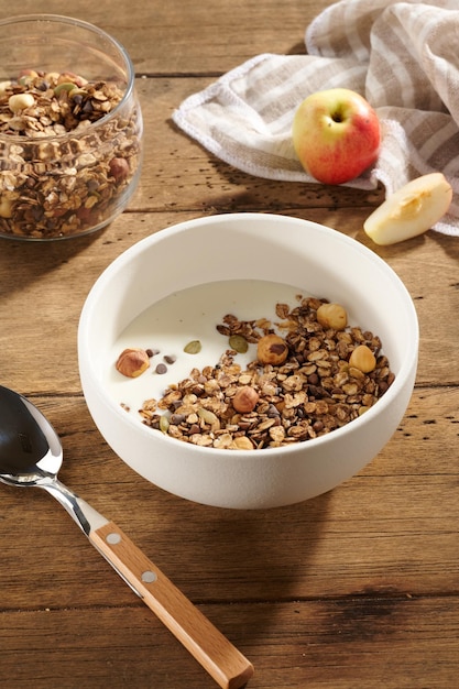 Granola met yoghurt en bessen in een witte kom op een houten tafel