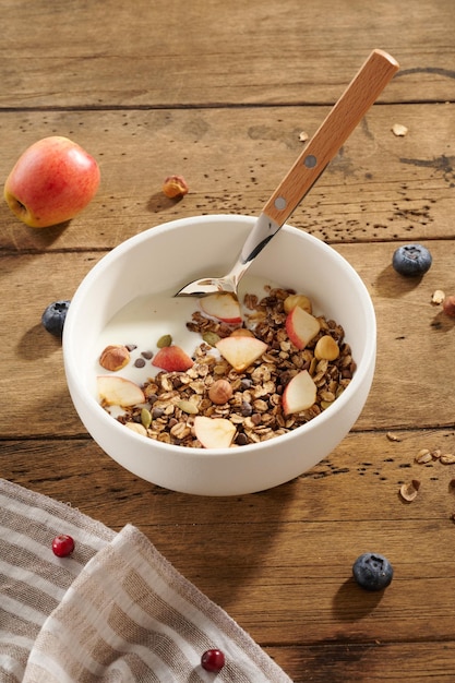 Foto granola met yoghurt en bessen in een witte kom op een houten tafel