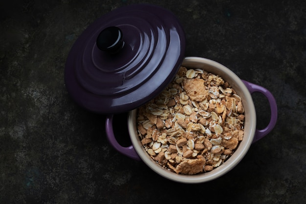Granola, muesli in ceramic pot with lid over a rustic table. Top View. Flat Lay