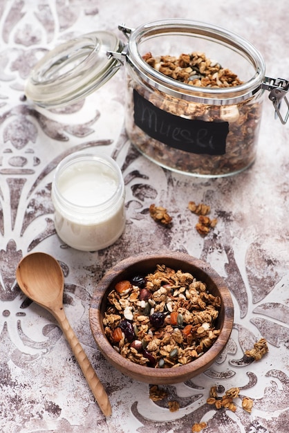 Granola muesli with dried fruits, nuts and seeds and a jar of yogurt for a healthy breakfast