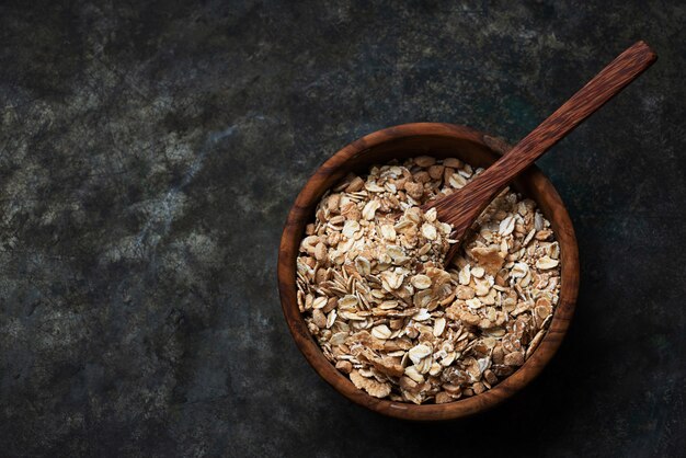 Granola, muesli in wooden bowl with wooden spoon over a rustic metal background. Top View. Flat Lay
