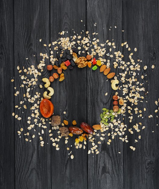 Granola Oatmeal scattered in a circle, dried fruits, nuts, raisins, seeds, on a wooden texturedFood 