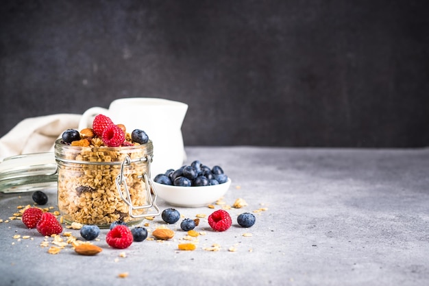 Granola with fresh berries in the glass jar Healthy dessert or snack at stone table