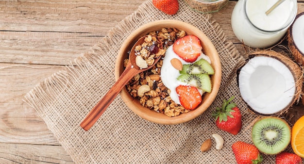 Muesli con yogurt greco e frutta su fondo di legno in stile rustico