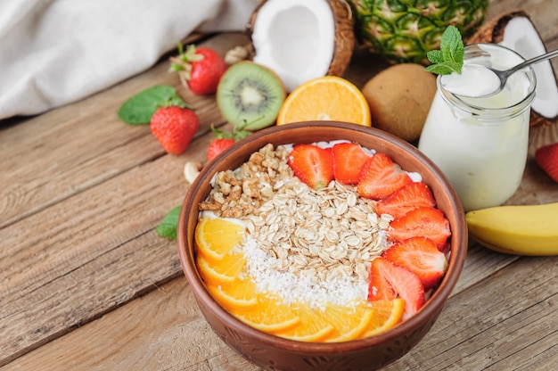 Granola with Greek yoghurt and fruit on a wooden background in a rustic style