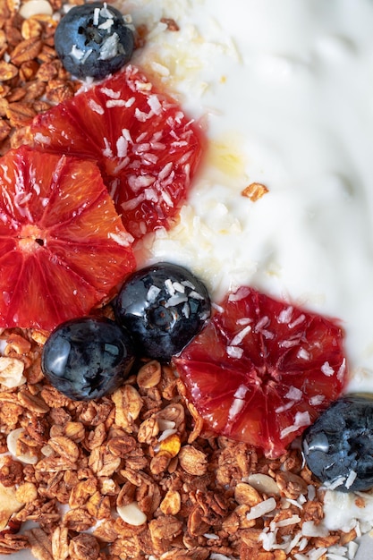 Photo granola with greek yogurt decorated with blood oranges blueberry and coconut close up